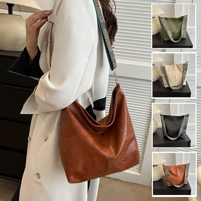 Brown bucket crossbody bag with turquoise patterned wide strap and metal clasp hardware