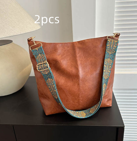 Rust brown bucket crossbody bag with turquoise patterned wide strap