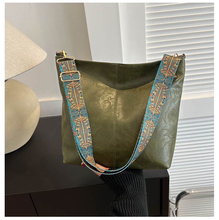 Olive green bucket crossbody bag with turquoise patterned wide strap