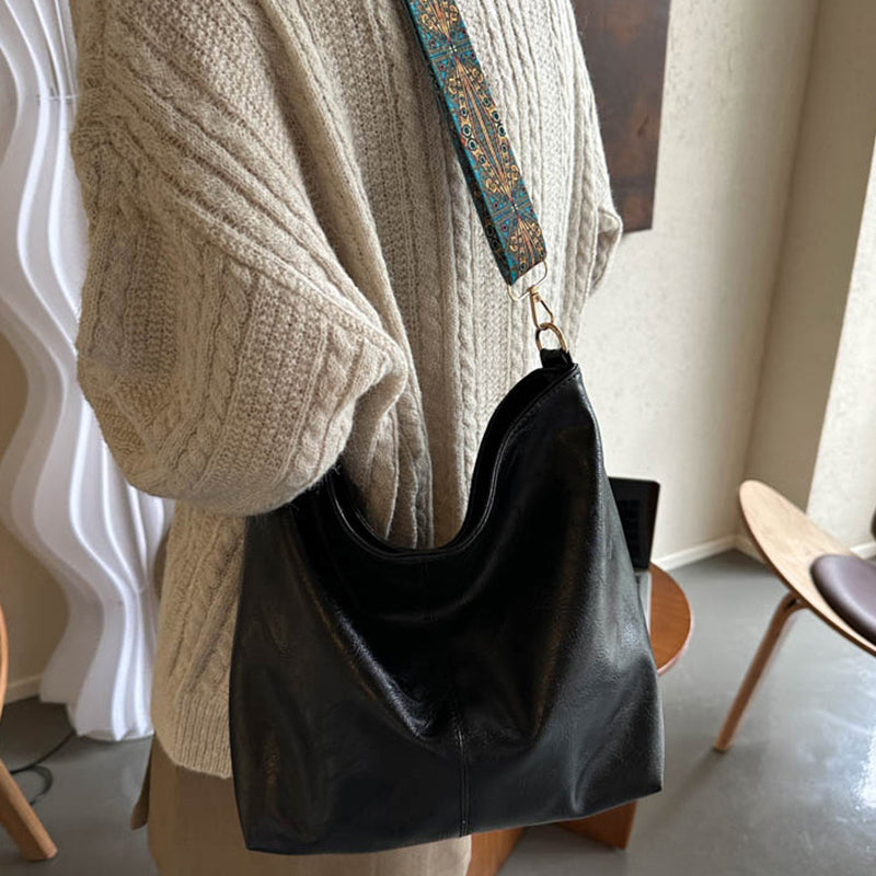 Black bucket shoulder bag with wide patterned strap and gold-tone hardware