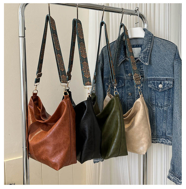 Bucket crossbody bag set in brown, black, green, and tan with patterned straps
