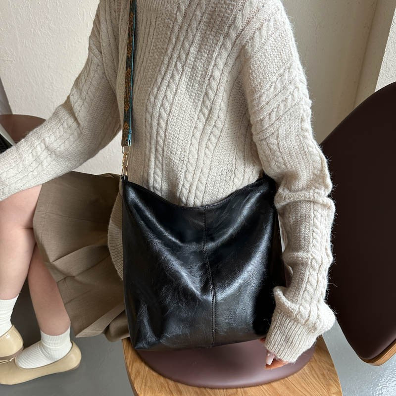 Black bucket crossbody bag with wide patterned strap